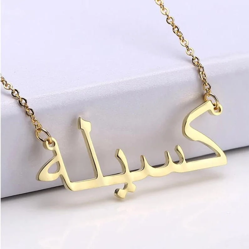 Personalised Urdu name necklace in gold on a white surface